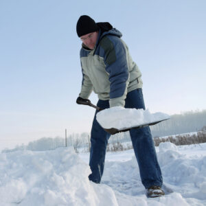Man clearing path from snow with snow shovel after heavy blizzard